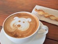 Latte Coffee art and biscuit stick on the wooden desk.