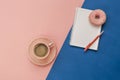 Latte Coffee cup, delicious pink donut with sprinkle, notebook for notes and pen on pink and blue paper background Royalty Free Stock Photo