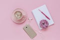 Latte Coffee cup, delicious pink donut with sprinkle, notebook and pen, smart phone with headphones on pink paper background Royalty Free Stock Photo