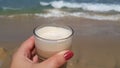 Latte coffee in female hand against sea waters