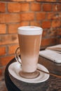 Latte Coffee macchiato in tall glasses with table settings in street cafe. Red brick wall background Royalty Free Stock Photo