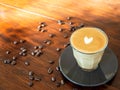 Latte hot coffee art design to white heart shape on top in clear glass with a coaster black color. Placed on a brown wooden table Royalty Free Stock Photo