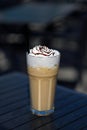 Latte macchiato coffee with cream in tall glass with straws on a dark table Royalty Free Stock Photo