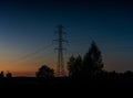 Lattice cross pylon and high voltage power lines at sunset with tree silhouette in front and copy space Royalty Free Stock Photo