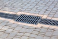 A lattice of a drainage paving system on a path made of square stone tiles. Royalty Free Stock Photo