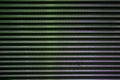 Latticed metal fence surface with jagged stripe elements and green spotlights