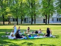 People rest on the green grass of the city park on a warm spring day