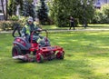Man on a riding lawn mower that has grass stuck to the wheels Royalty Free Stock Photo