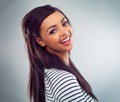 Laugh as much as you can. a young woman posing against a grey background.