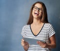 Laugh without fear of the future. Studio shot of a young woman using her digital tablet against a grey background.