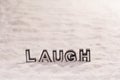 Laugh word on white sand