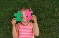 A laughable girl is playing with puzzles, closing her eyes with details Royalty Free Stock Photo