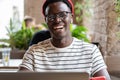 Laughing African American hipster man using laptop, talking online in video chat with friends in cafe Royalty Free Stock Photo