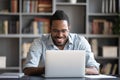 Laughing African American man using laptop, looking at screen Royalty Free Stock Photo