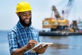 Laughing african american offshore worker with digger and ocean Royalty Free Stock Photo