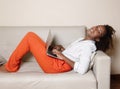Laughing african american woman with notebook on couch