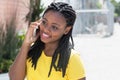 Laughing african american woman in a yellow shirt at mobile phone Royalty Free Stock Photo