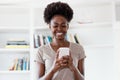 Laughing african american young adult woman installing app on phone