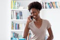 Laughing afro american young adult woman at mobile phone