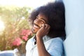 Laughing afro man leaning against wall talking on mobile phone Royalty Free Stock Photo