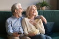 Laughing aged couple, man and woman watching tv and eating popcorn Royalty Free Stock Photo