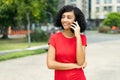 Laughing arabic young adult woman talking with boyfriend at mobile phone