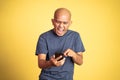 laughing asian bald man looking at a smart phone