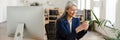 The laughing Asian woman holding a phone in her hands and looking at something in it in a light office Royalty Free Stock Photo