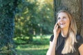 Laughing attractive young girl is phoning in the park