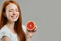 Laughing awesome charming girl with closed eyes is holding a half of grapefruit