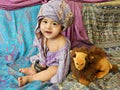 Laughing baby boy dressing in turban sits on Asian fabrics