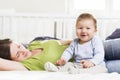 Laughing baby boy sitting in bed together with his mother. Royalty Free Stock Photo