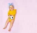 Laughing baby girl lay with football ball in bed Royalty Free Stock Photo