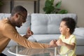 Black father laughing playing with small kid at home