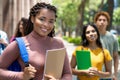 Laughing black female student with dreadlocks and group of latin american and caucasian young adults Royalty Free Stock Photo