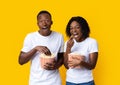 Laughing black man and woman eating popcorn on yellow background Royalty Free Stock Photo