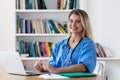 Laughing blond nurse working at computer