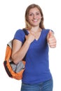 Laughing blonde student with backpack showing thumb up