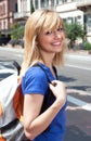 Laughing blonde student with bag in the city