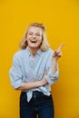 Laughing blonde woman with her index finger outstreched over yellow