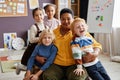 Laughing boy and other little learners standing by their teacher