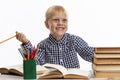 The laughing boy sits at the table and does his homework. White background Royalty Free Stock Photo