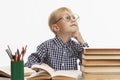 The laughing boy sits at the table and does his homework. White background Royalty Free Stock Photo