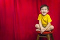 Laughing Boy Sitting on Stool in Front of Curtain Royalty Free Stock Photo