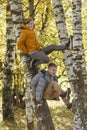 Laughing boys friends sit on trees in the park on a sunny autumn day. Friendship and rest together. Vertical