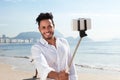 Laughing brazilian man making picture with a selfie stick at Copacabana beach Royalty Free Stock Photo
