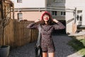 Laughing brunette girl in vintage short overall and red beret posing outside with hands up and enjoys sunshine. Cute