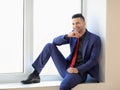 Laughing business man relaxing on window sill Royalty Free Stock Photo