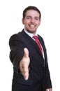 Laughing businessman in black suit reaching hand for handshake Royalty Free Stock Photo