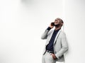 Laughing businessman leaning against white wall talking with mobile phone Royalty Free Stock Photo